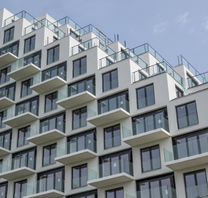 Wit appartementengebouw met getrapte balkons tegen een blauwe lucht