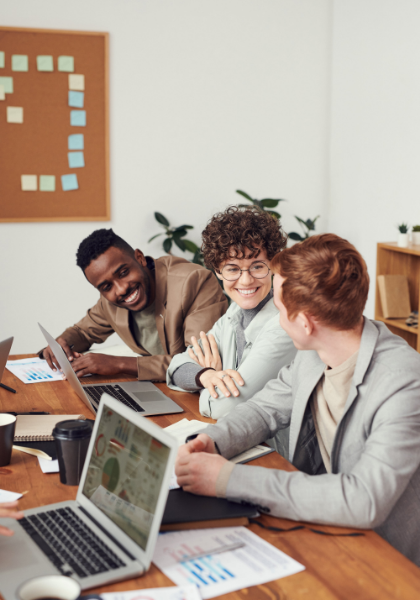 Drie mensen overleggen aan tafel met een laptop